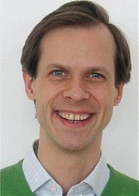 Porträt von Mag. pharm. Stephan Höbinger, lächelnd, in grünem Pullover