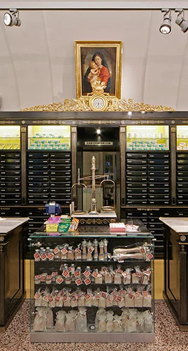 Verkaufstisch mit goldenen Rosetten vor den schwarz lackierten Schubladenschränken und Regalen mit Pflegeprodukten